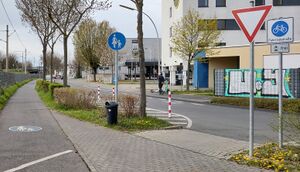 Übergang von einem separaten Radweg auf eine querende Fahrradstraße. Zu sehen ist die Beschilderung beim Übergang vom Radweg auf die Fahrradstraße mit den Zeichen 244.1 (Fahrradstraße, hier mit KFZ-Verkehr freigegeben) und 205 (Vorfahrt gewähren)